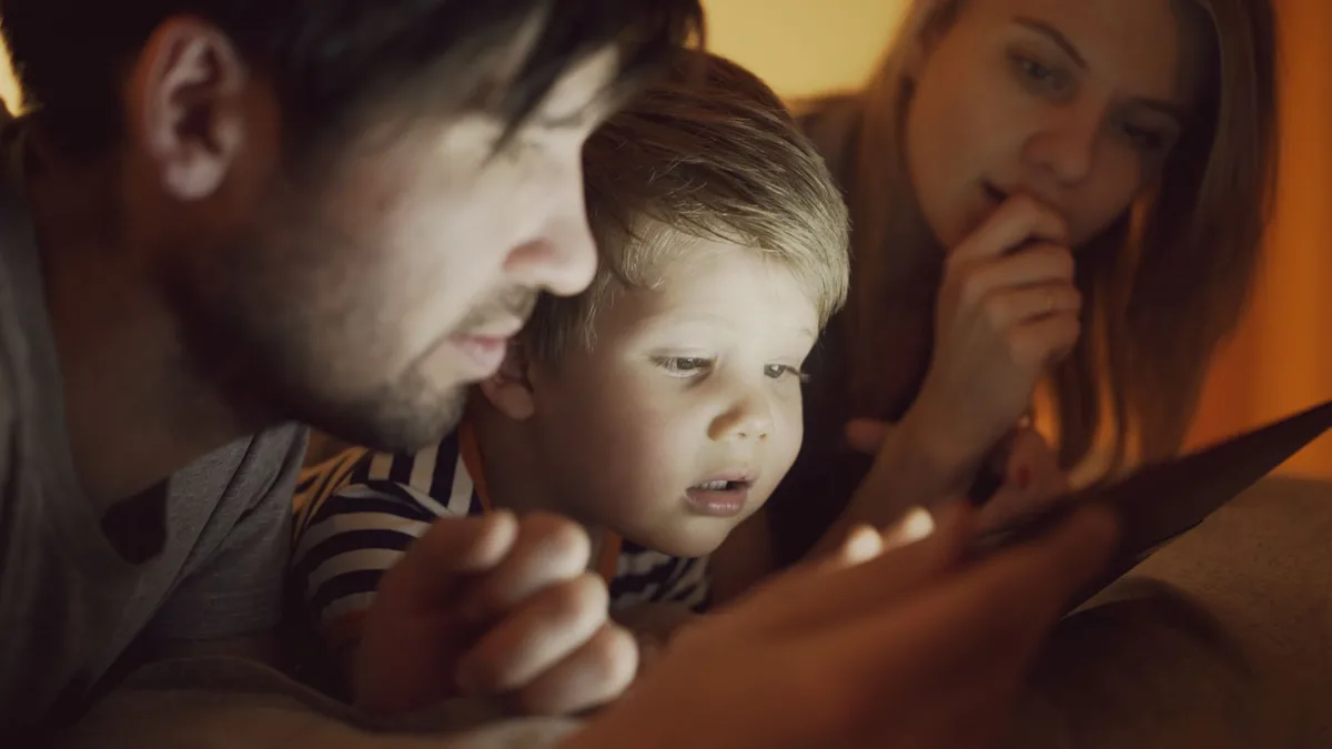 Enfant avec téléphone et tablette, panier de recharge visible