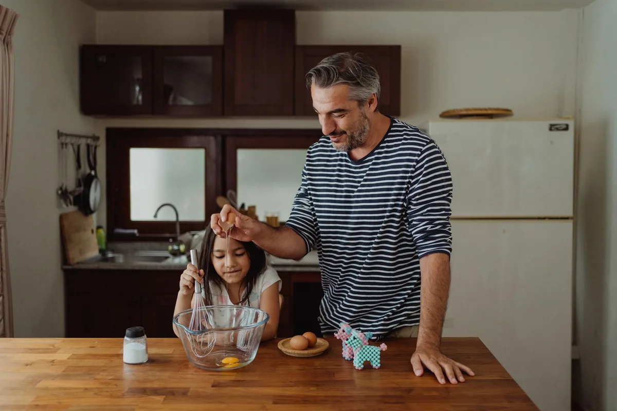 Parent et enfant discutant à la maison avant une sortie, en préparant la liste de courses.