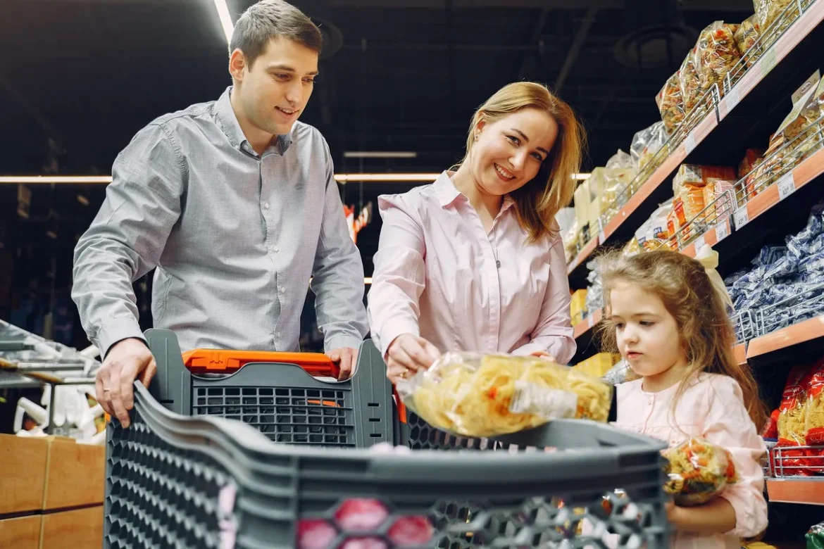 Parent et enfant dans une allée de supermarché, l'enfant tendant la main vers les rayons, parent calme et attentif.
