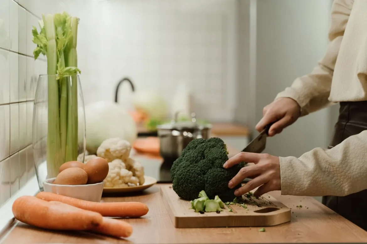 Mains préparant des aliments sains : œufs, légumes frais et verre d'eau sur un plan de travail