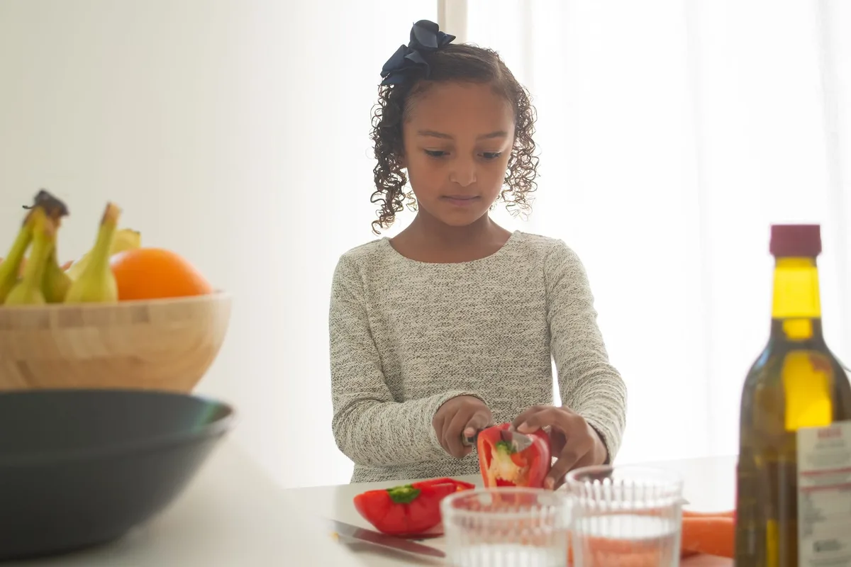 Enfants d'âges différents effectuant des tâches culinaires adaptées à leur niveau.