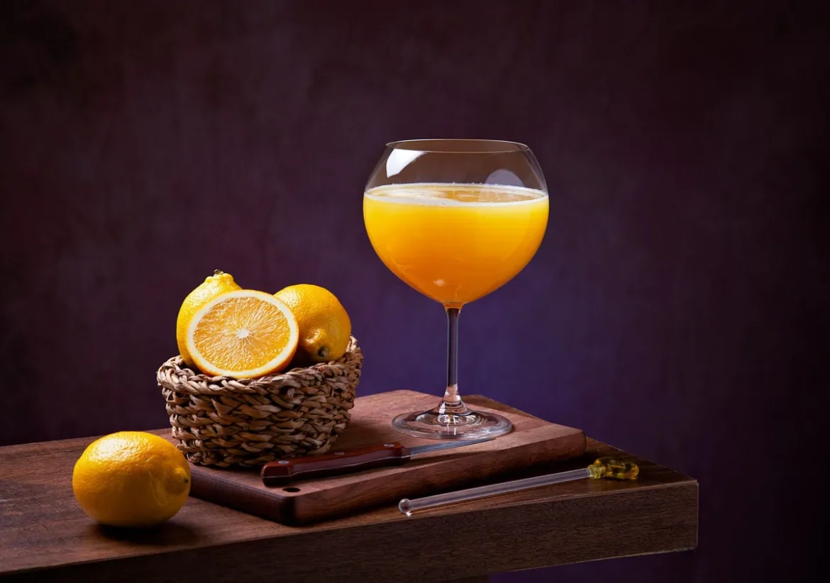 Verre de jus de fruits frais versé sur un plan de travail avec fruits entiers et blender