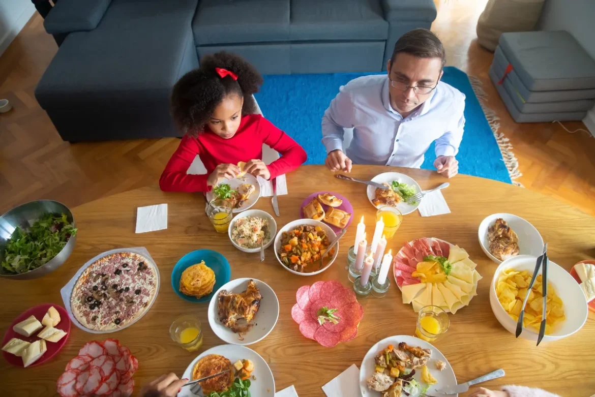 Famille partageant un repas autour d'une table, enfant assis calmement avec ses parents.