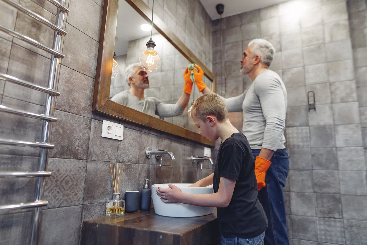 Un enfant se lave les mains devant un miroir en imitant le geste du lavage