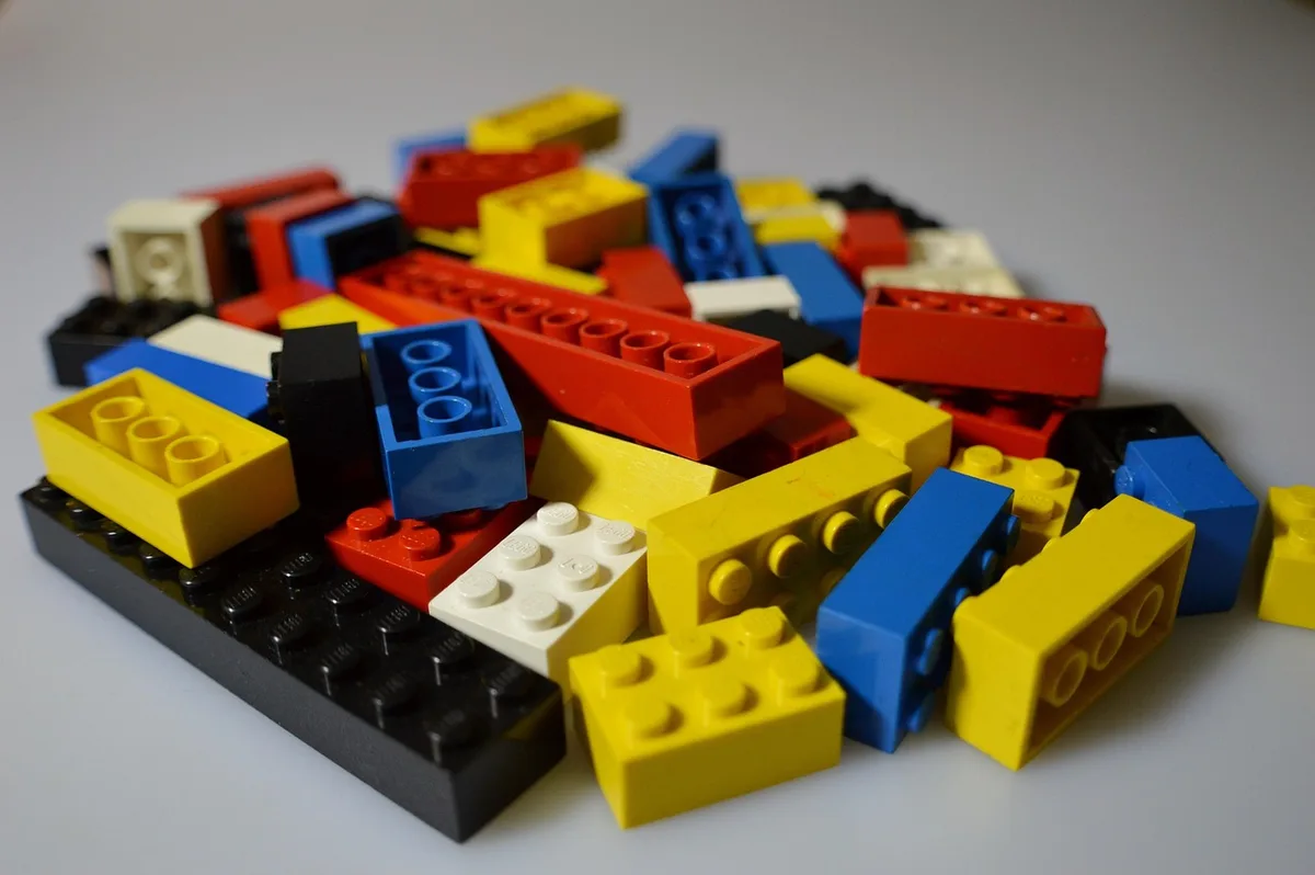 Enfants jouant avec des jouets variés : blocs de construction, instruments de musique et jeux non genrés.