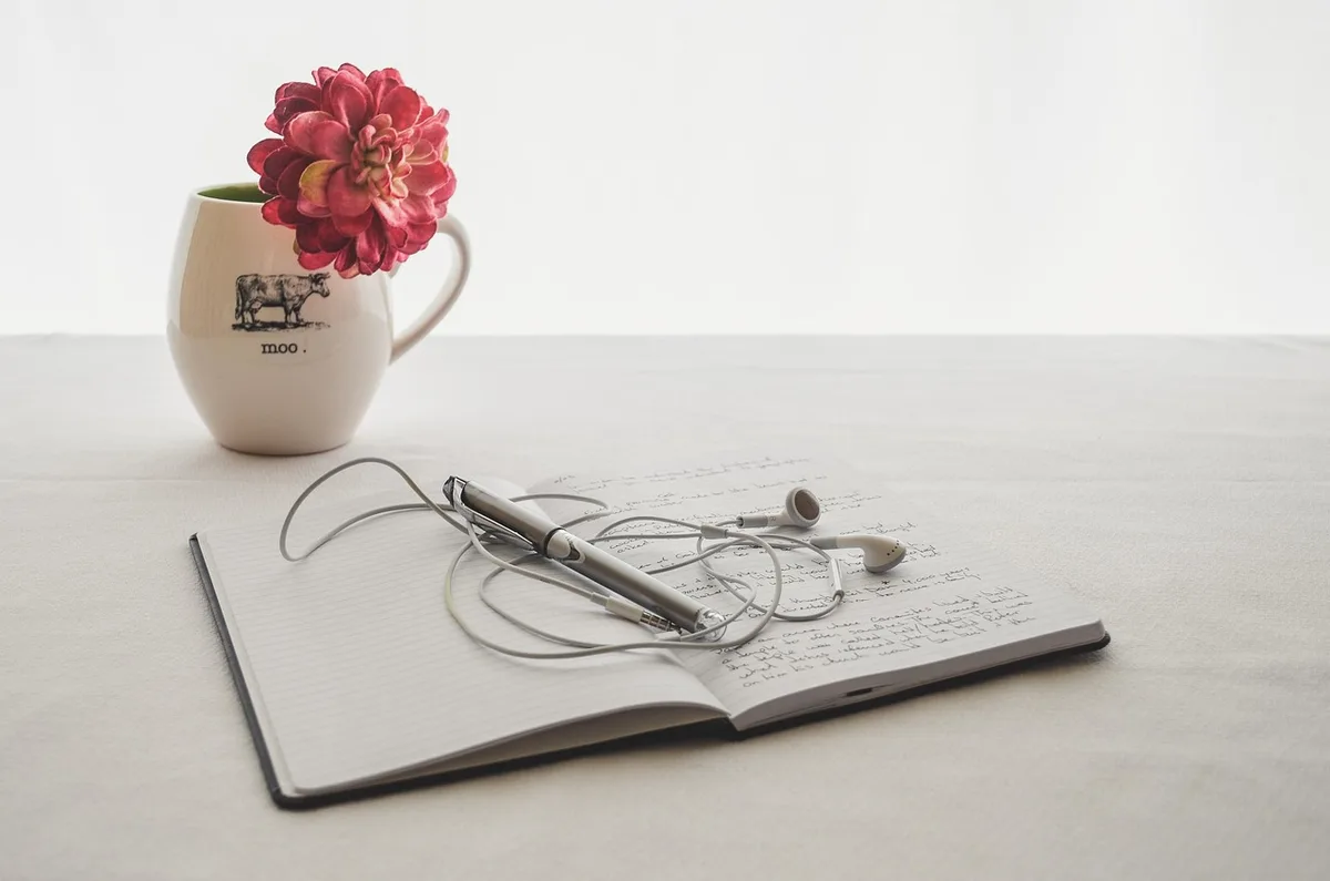Personne écrivant un carnet de gratitude sur une table éclairée