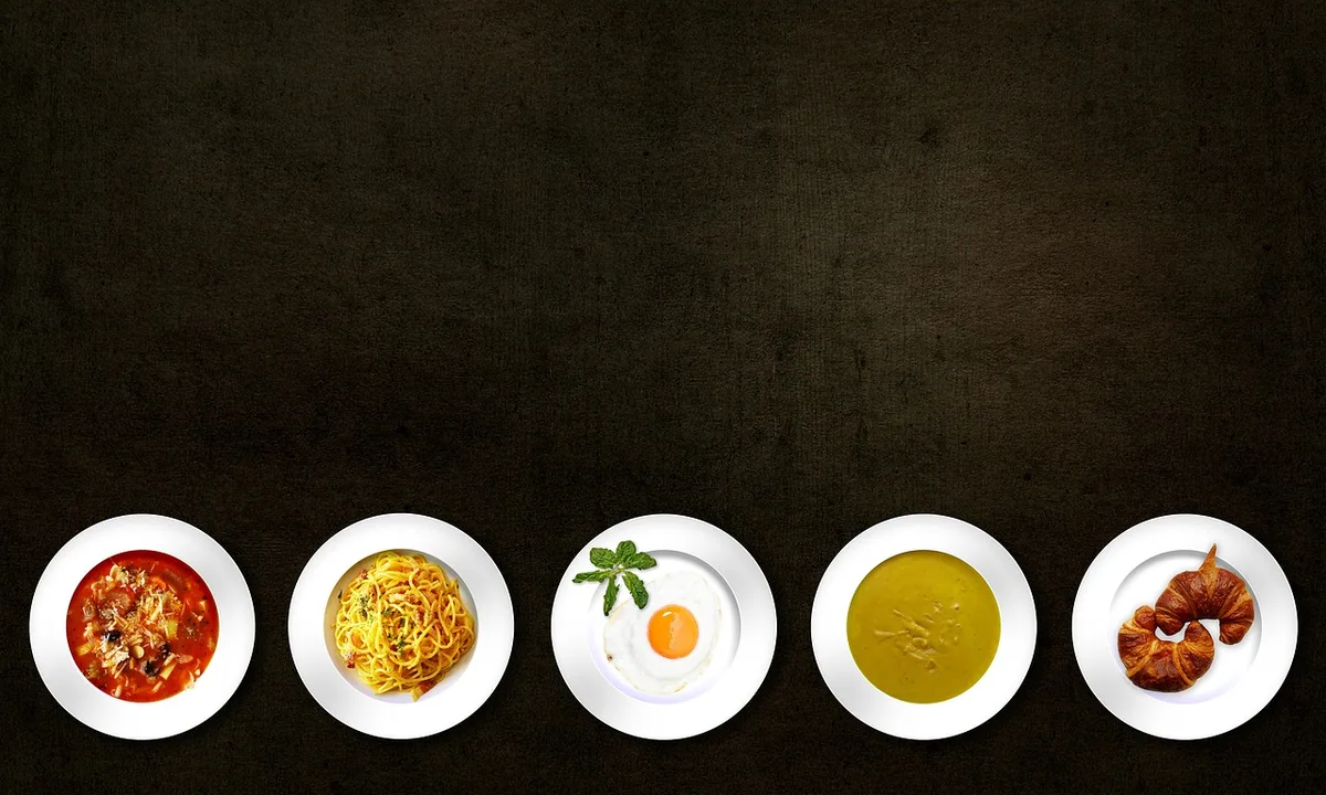 Trois assiettes montrant différentes façons de saupoudrer la levure nutritionnelle sur des pâtes, une salade et une soup