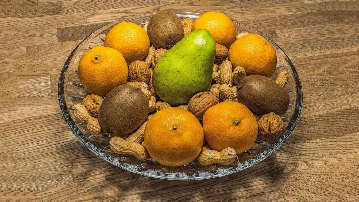 Main d'une personne versant de la levure nutritionnelle dorée sur un bol de légumes et pâtes chauds