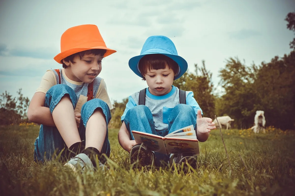 Parent et enfant feuilletant un album jeunesse près d'une fenêtre en journée