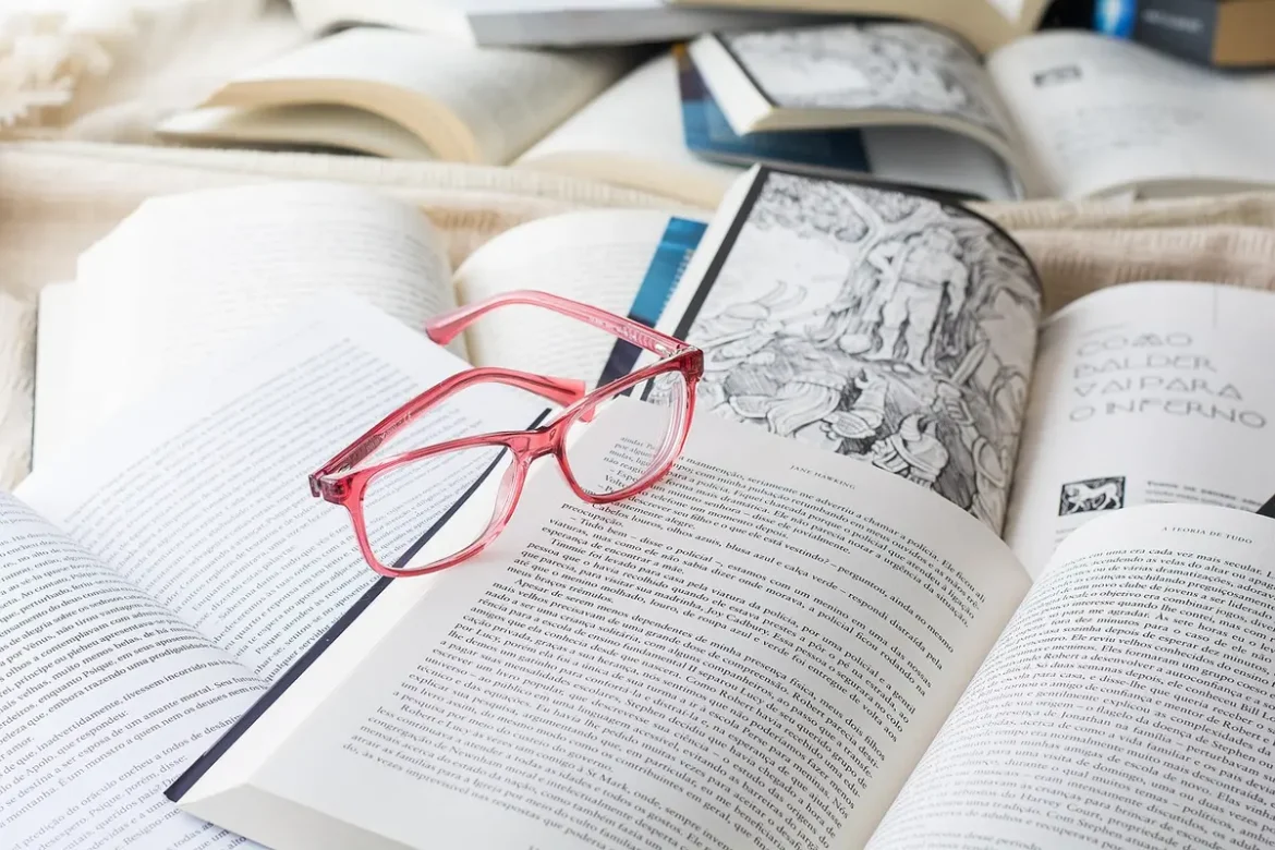 Coin lecture en journée près d'une grande fenêtre, mains anonymes feuilletant un livre
