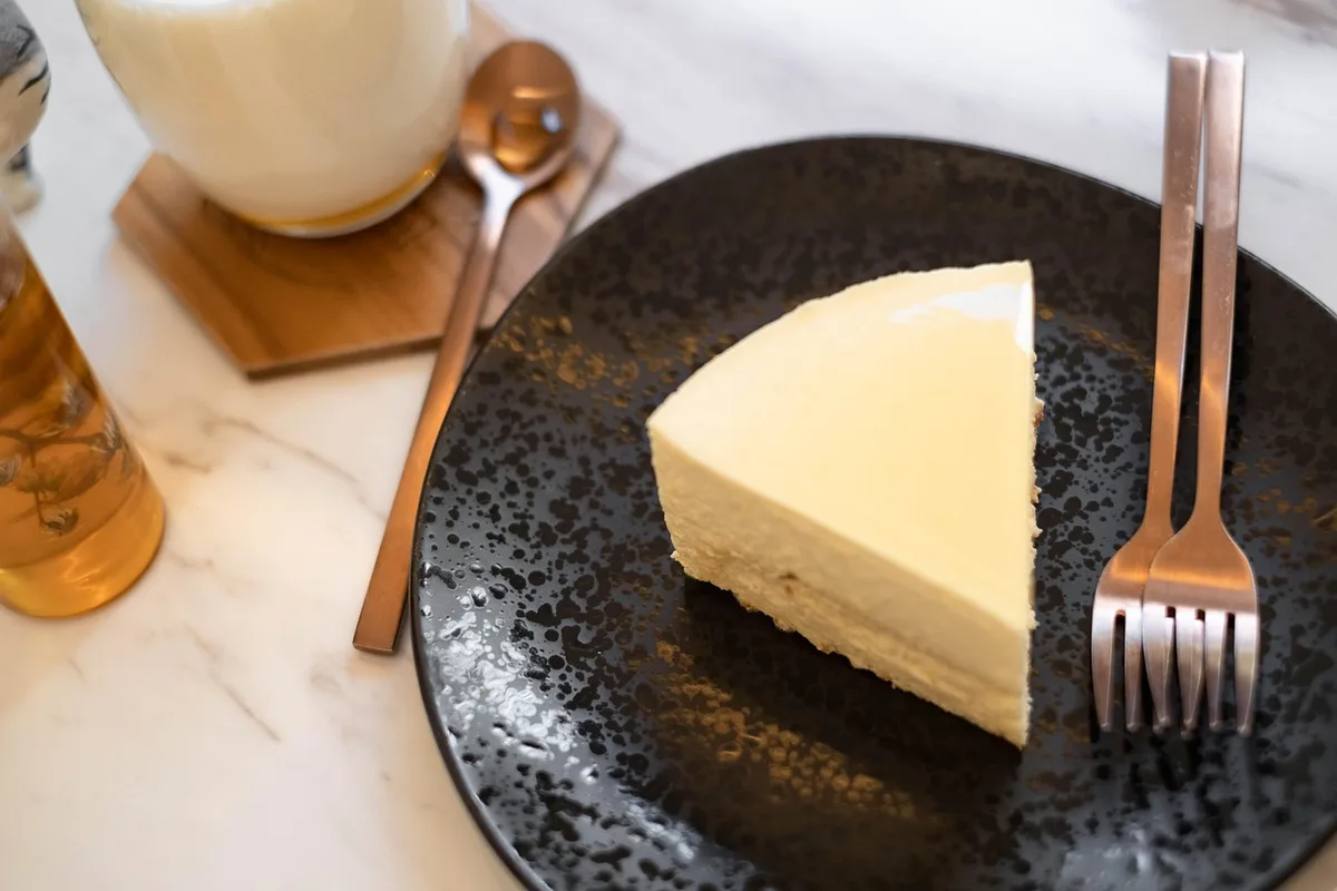 mains utilisant une spatule pour lisser des couches de cheesecake